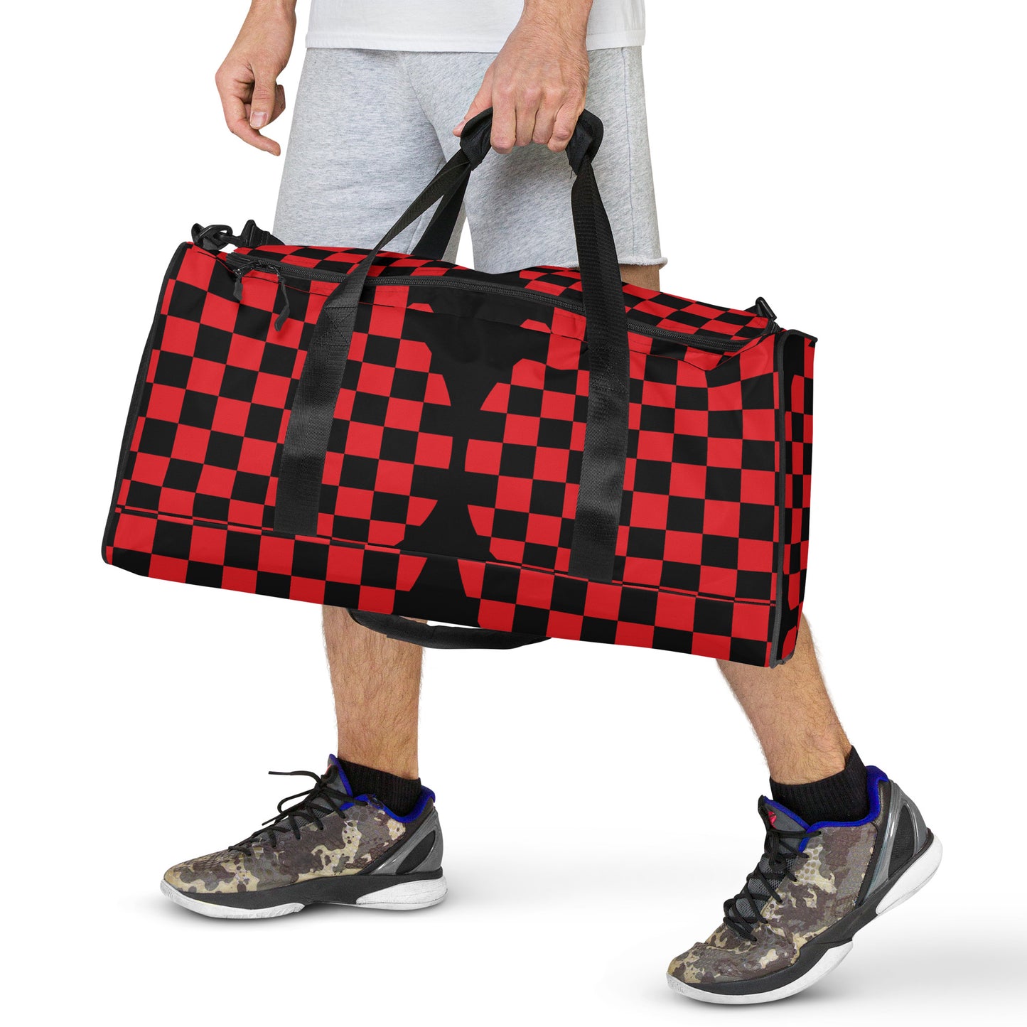 Person holding a red and black checkered duffel bag on a white background
