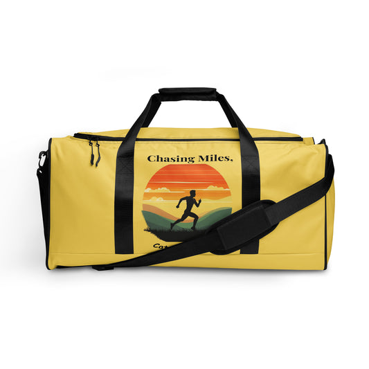 Yellow duffel bag with 'Chasing Miles' design on a white background