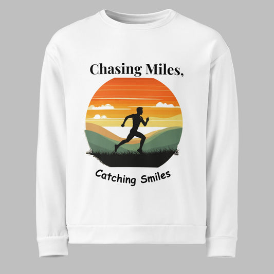 White sweatshirt with a graphic of a runner and sunset design, text 'Chasing Miles, Catching Smiles' on a white background.